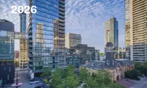 Park surrounded by highrises and a historic yellow brick fire house with clock tower.